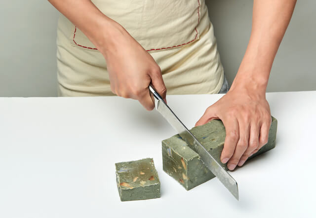 man cutting a handmade soap with a knife